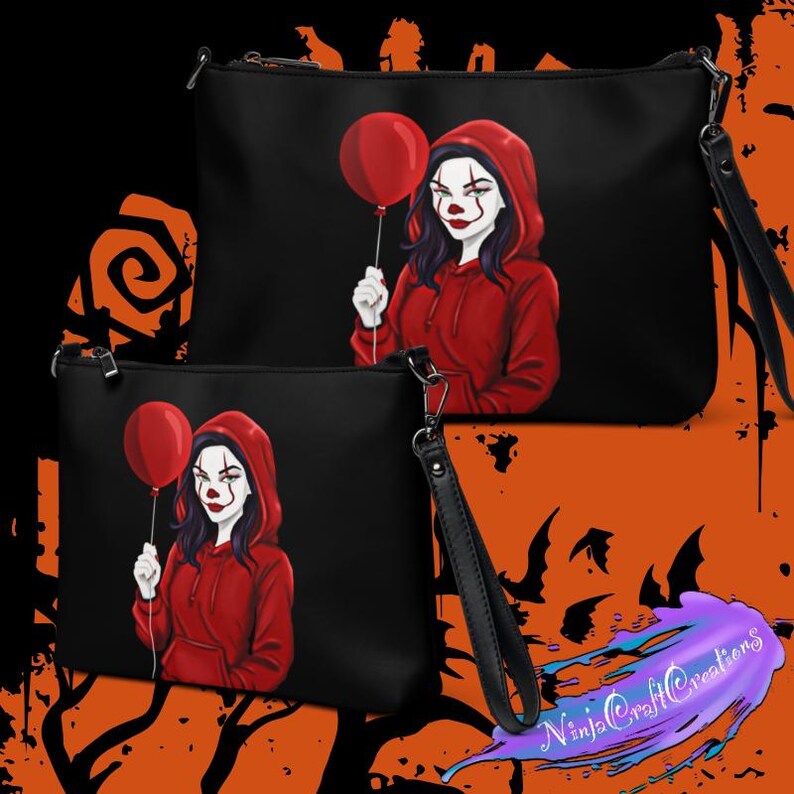 May include: Black clutch bags featuring a graphic of a person in a red hoodie holding a red balloon, with clown-like makeup. The bags have a wrist strap and a zipper closure. The background is black and orange.