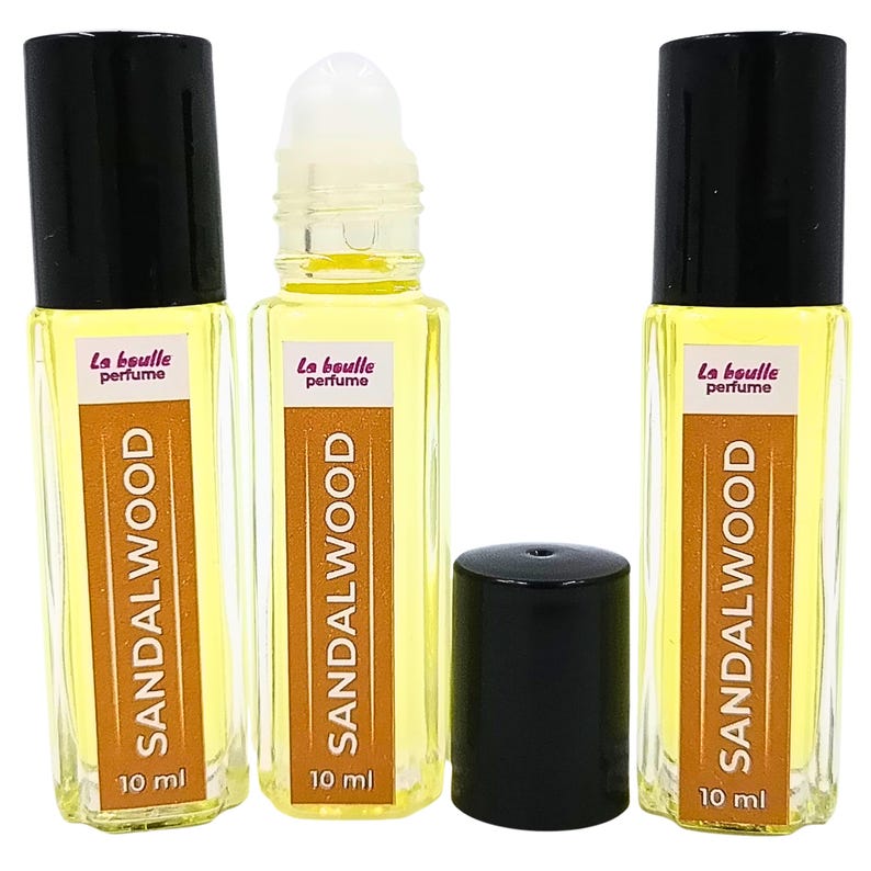 Pode incluir: Tr&ecirc;s frascos de vidro &acirc;mbar de 10 ml com tampas pretas. Cada frasco cont&eacute;m um l&iacute;quido amarelo e tem um r&oacute;tulo branco com o texto "La boulle perfume" e "SANDALWOOD" impresso em preto.