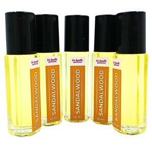 Pode incluir: Cinco frascos de 10 ml de &oacute;leo de perfume de s&acirc;ndalo. Os frascos s&atilde;o de vidro transparente com tampas pretas e etiquetas que dizem "La Boule Perfume" e "Sandalwood".