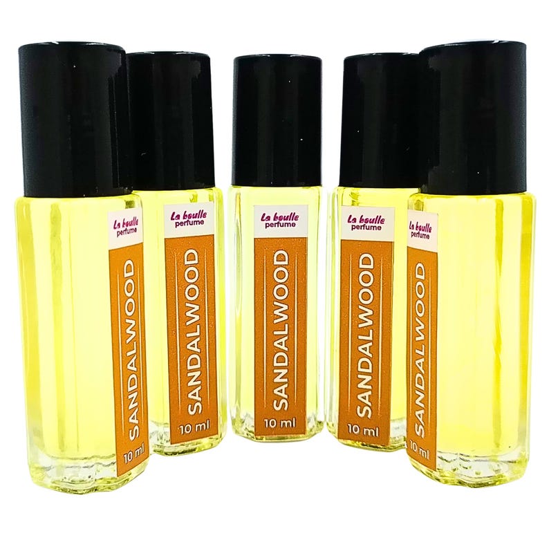 Pode incluir: Cinco frascos de 10 ml de &oacute;leo de perfume de s&acirc;ndalo. Os frascos s&atilde;o de vidro transparente com tampas pretas e etiquetas que dizem "La Boule Perfume" e "Sandalwood".