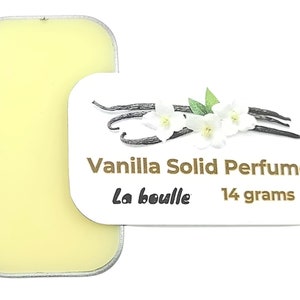 May include: A small, round tin of vanilla solid perfume, labeled "Vanilla Solid Perfume" with the brand name "La Bouille" and the weight "14 grams". The tin is open, revealing the yellow solid perfume inside.