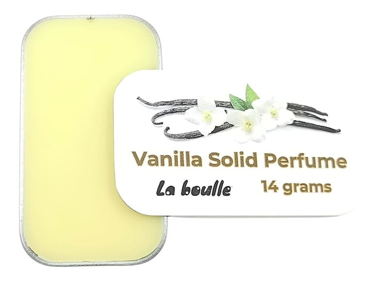 May include: A small, round tin of vanilla solid perfume, labeled "Vanilla Solid Perfume" with the brand name "La Bouille" and the weight "14 grams". The tin is open, revealing the yellow solid perfume inside.