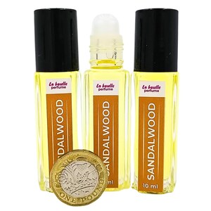 Pode incluir: Tr&ecirc;s frascos de perfume de s&acirc;ndalo de 10 ml em formato roll-on. Os frascos s&atilde;o de vidro transparente com tampas pretas e etiquetas que dizem "La boulle perfume" e "SANDALWOOD".