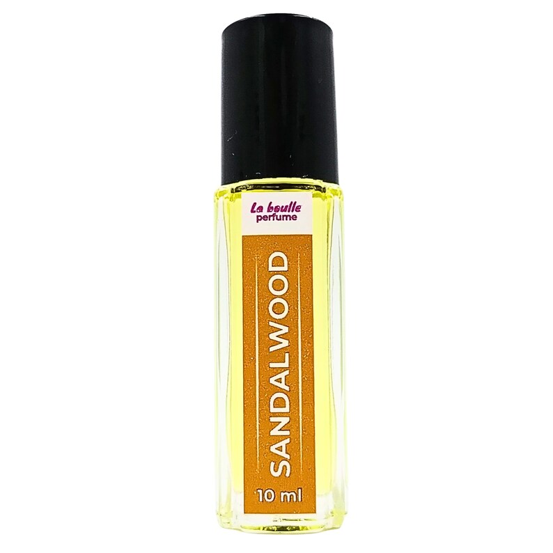 Pode incluir: Um frasco de vidro transparente com uma tampa preta e um r&oacute;tulo amarelo. O r&oacute;tulo diz "La bouille perfume" e "SANDALWOOD" em rosa. O frasco cont&eacute;m 10 ml de perfume de s&acirc;ndalo.