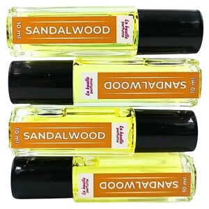 Pode incluir: Quatro frascos de 10 ml de &oacute;leo de perfume de s&acirc;ndalo. Cada frasco tem uma tampa preta e um r&oacute;tulo que diz "La Boulle Perfume" e "SANDALWOOD".