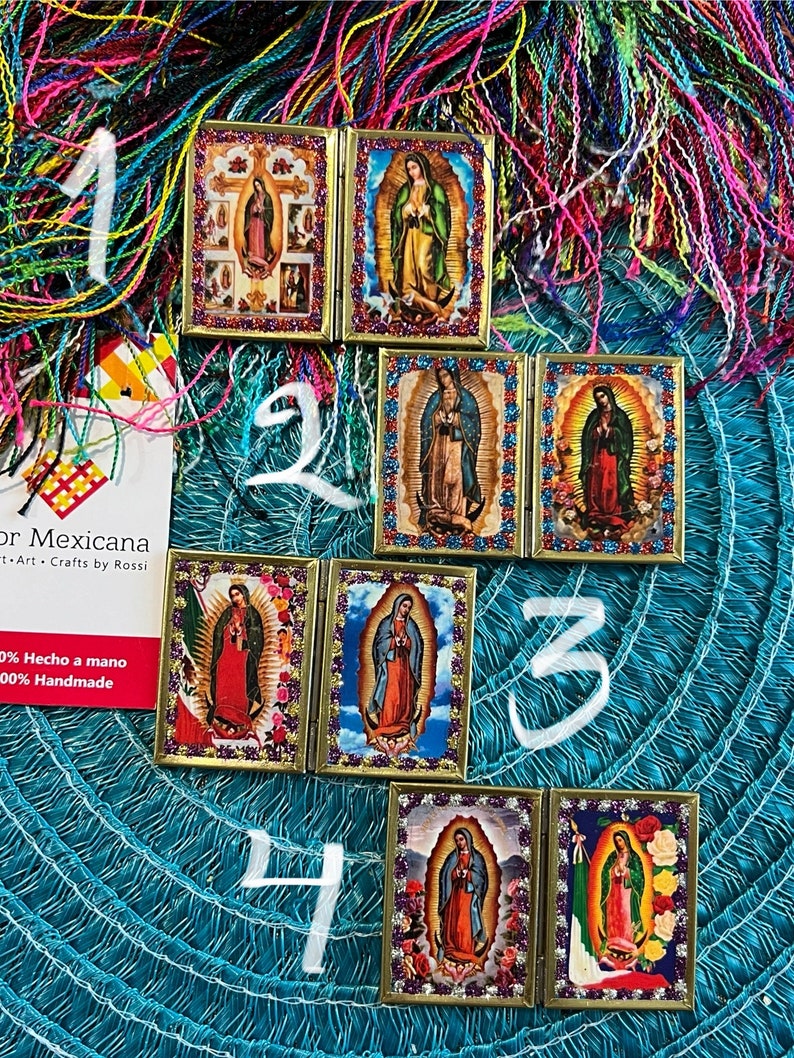 May include: Four different folding picture frames with images of the Virgin Mary. Each frame is decorated with glitter and has a gold trim. The frames are numbered 1 through 4.