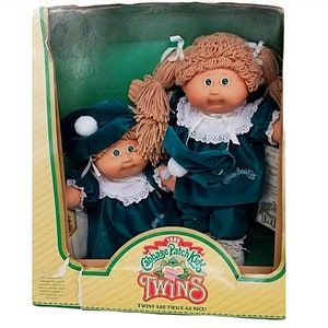May include: Vintage Cabbage Patch Kids Twins dolls in their original box. The dolls are dressed in teal velvet outfits with white lace collars and matching hats. The box features the Cabbage Patch Kids logo and the text "Twins are twice as nice!"