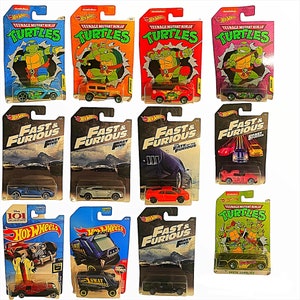 May include: A collection of Hot Wheels toy cars, including Teenage Mutant Ninja Turtles and Fast & Furious themed vehicles. The cars are packaged on colorful cardboard backings, featuring graphics and logos.