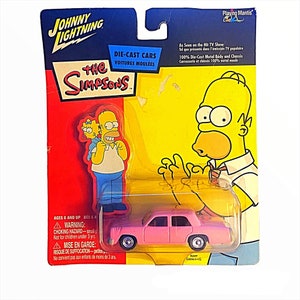 Peut inclure: Une voiture rose moulée sous pression des Simpsons, emballée sur une carte rouge, jaune et bleue. La carte présente Homer Simpson et le logo de l'émission. L'emballage comprend le texte "Johnny Lightning" et "Voitures Moulées".
