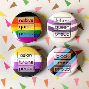 Puede incluir: Cuatro botones redondos con diferentes banderas de orgullo y el texto "native queer proud", "latinx queer proud", "asian trans proud" y "black trans proud".