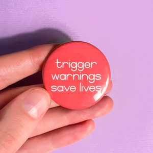 May include: A red button with the text "trigger warnings save lives" in white.