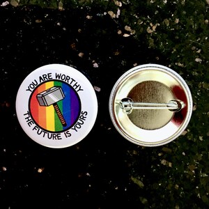 Puede incluir: Un bot&oacute;n blanco con un fondo de arco&iacute;ris y un martillo de dibujos animados con el texto "You are worthy the future is yours". La parte posterior del bot&oacute;n es plateada con un alfiler.