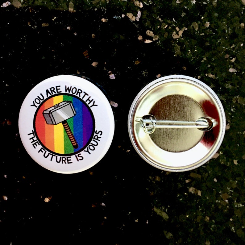 Puede incluir: Un bot&oacute;n blanco con un fondo de arco&iacute;ris y un martillo de dibujos animados con el texto "You are worthy the future is yours". La parte posterior del bot&oacute;n es plateada con un alfiler.