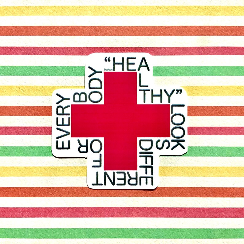 May include: A white sticker with a red cross in the center. The words "EVERY BODY LOOKS DIFFERENT" are written around the cross. The text "HEAL THY" is written inside the cross.