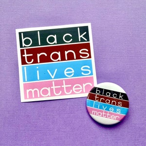 Puede incluir: Una pegatina blanca con el texto "black trans lives matter" en letras negras y rosas sobre un fondo morado. Un bot&oacute;n redondo con el mismo texto en letras negras y rosas sobre un fondo blanco.