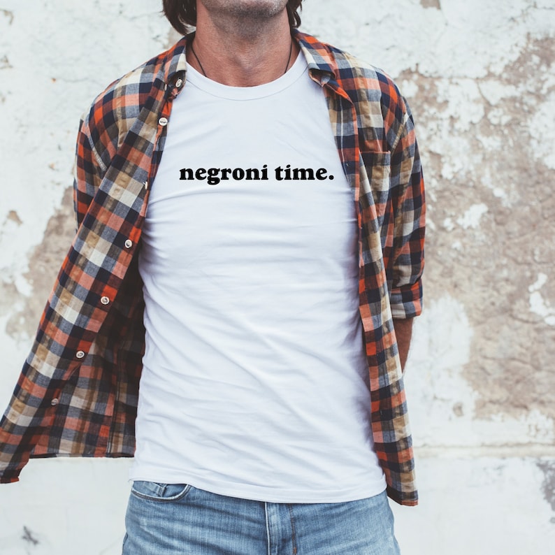 Może przedstawiać: Biała koszulka z nadrukiem "negroni time." w kolorze czarnym.