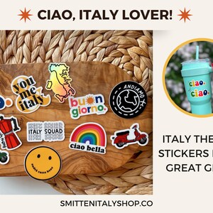 May include: A collection of colorful Italian-themed stickers featuring phrases like "Ciao", "You & Me Italy", "Buon Giorno", and "Ciao Bella". The stickers are arranged on a wooden board with a wicker background. The text "ITALY THEMED STICKERS MAKE GREAT GIFTS!" is displayed below the image.