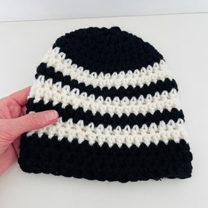 Könnte beinhalten: Gestrickte Mütze mit schwarzen und weißen Streifen.