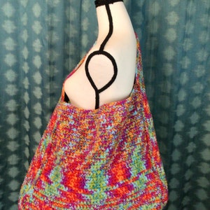May include: A colorful crocheted tote bag with a multi-colored yarn design. The bag is large and roomy, with a wide opening and a flat bottom.