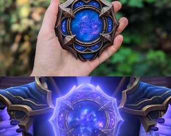 May include: A close-up of a blue and gold pendant with a swirling galaxy design inside. The pendant is a circular shape with a detailed frame.