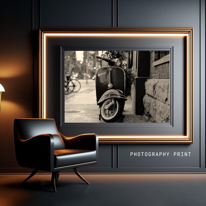 May include: A black and white photograph of a vintage scooter parked on a city street. The scooter is in focus, while the background is blurred. The image is framed in a gold frame and labeled "PHOTOGRAPHY PRINT".