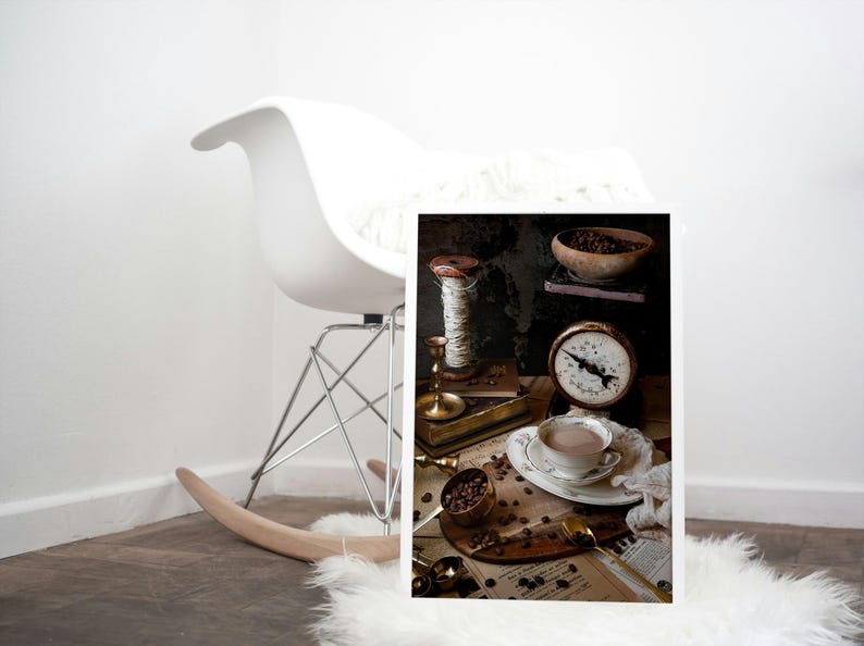 K&ouml;nnte beinhalten: Eine Vintage-Stillleben mit einer Tasse Kaffee, einer Waage, einer Garnrolle und Kaffeebohnen auf einem St&uuml;ck Papier mit Noten.