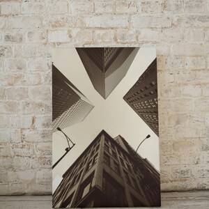 May include: A black and white photograph of a city skyline with tall buildings viewed from below. The buildings are arranged in a symmetrical pattern, creating a sense of perspective and depth.