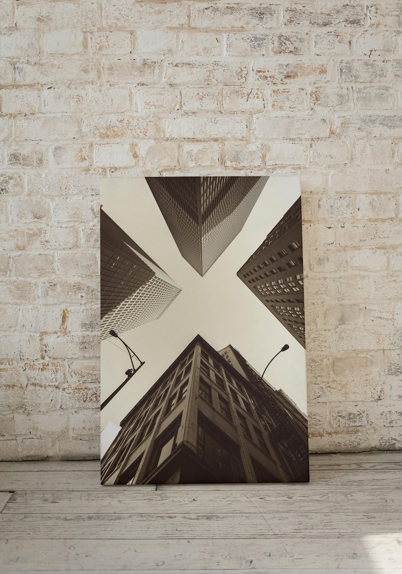 May include: A black and white photograph of a city skyline with tall buildings viewed from below. The buildings are arranged in a symmetrical pattern, creating a sense of perspective and depth.