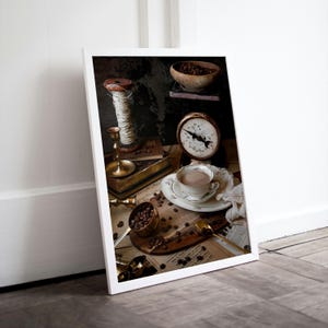 K&ouml;nnte beinhalten: Ein Stillleben mit einer Tasse Kaffee, Kaffeebohnen, einer Waage, einer Garnrolle, einem Kerzenhalter und einem Buch. Das Bild ist auf einem rustikalen Hintergrund mit Vintage-&Auml;sthetik platziert.