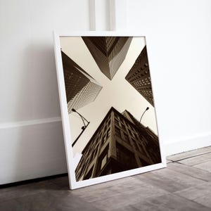 May include: A black and white photograph of four tall buildings in a city. The buildings are seen from a low angle, looking up at the sky. The buildings are all different heights and have different architectural styles.