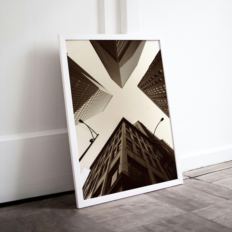 May include: A black and white photograph of four tall buildings in a city. The buildings are seen from a low angle, looking up at the sky. The buildings are all different heights and have different architectural styles.