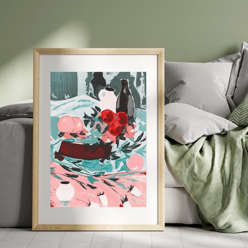 Puede incluir: Una pintura de bodeg&oacute;n con un mantel rosa y verde con fruta roja, jarras de cer&aacute;mica blanca y una botella marr&oacute;n oscura. La pintura est&aacute; enmarcada en un marco de madera claro.