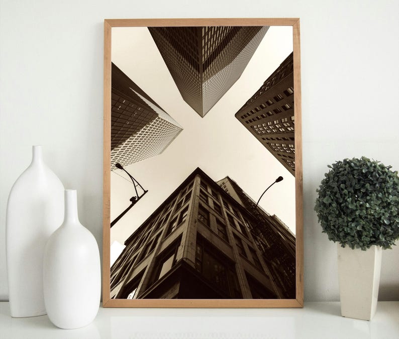May include: A black and white photograph of tall buildings in a city. The buildings are arranged in a starburst pattern, with the tops of the buildings pointing towards the centre of the image. The sky is a light grey colour.