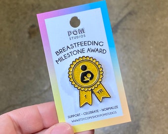 Könnte beinhalten: Goldfarbene Emaille-Anstecknadel mit einer schwarzen Silhouette einer Person, die ein Baby stillt. Die Anstecknadel ist wie ein Band geformt mit den Worten "1 YR" darauf. Die Anstecknadel befindet sich auf einer Karte, auf der "Breastfeeding Milestone Award" und "Support. Celebrate. Normalize." steht.