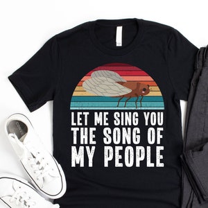 May include: Black t-shirt with a vintage-style graphic of a cicada and the text "Let me sing you the song of my people".