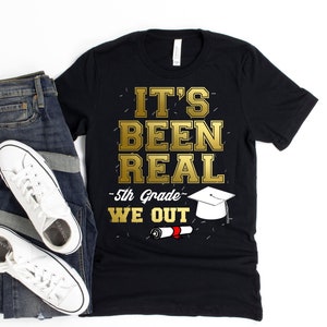 Op de afbeelding: Zwart T-shirt met gouden tekst die "It's Been Real - 5th Grade - We Out" zegt met een afbeelding van een afstudeerhoed en een diploma.