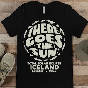 May include: Black t-shirt with a white graphic of a sun with the text "There Goes The Sun" and "Total Solar Eclipse Iceland August 12, 2026".