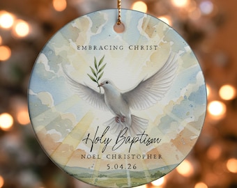 Può includere: Ornamento rotondo in ceramica raffigurante una colomba bianca con un ramo d'ulivo, su uno sfondo di cielo ad acquerello. Il testo include "Embracing Christ" e "Holy Baptism", più un nome e una data.