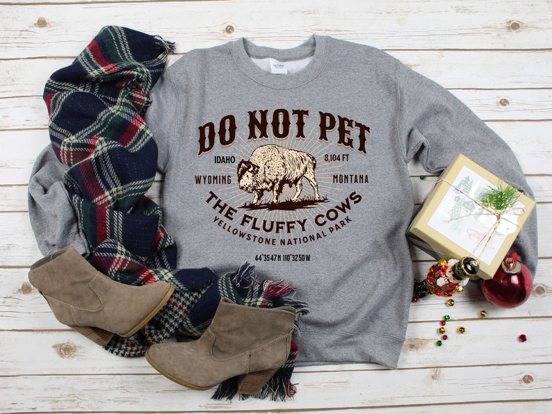 May include: Gray sweatshirt with a brown graphic of a bison and the text "DO NOT PET THE FLUFFY COWS YELLOWSTONE NATIONAL PARK 44 3547N 110 3250W 8,104 FT IDAHO WYOMING MONTANA".