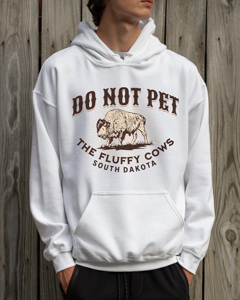 May include: White hooded sweatshirt with a brown graphic that says "Do Not Pet The Fluffy Cows South Dakota" and a drawing of a bison.