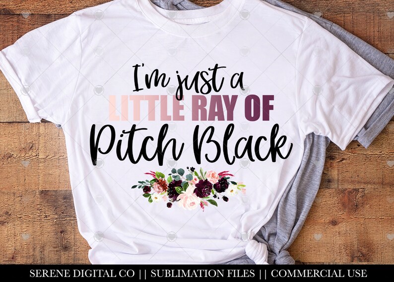 May include: White t-shirt with a black floral design and the text "I'm just a little ray of pitch black".