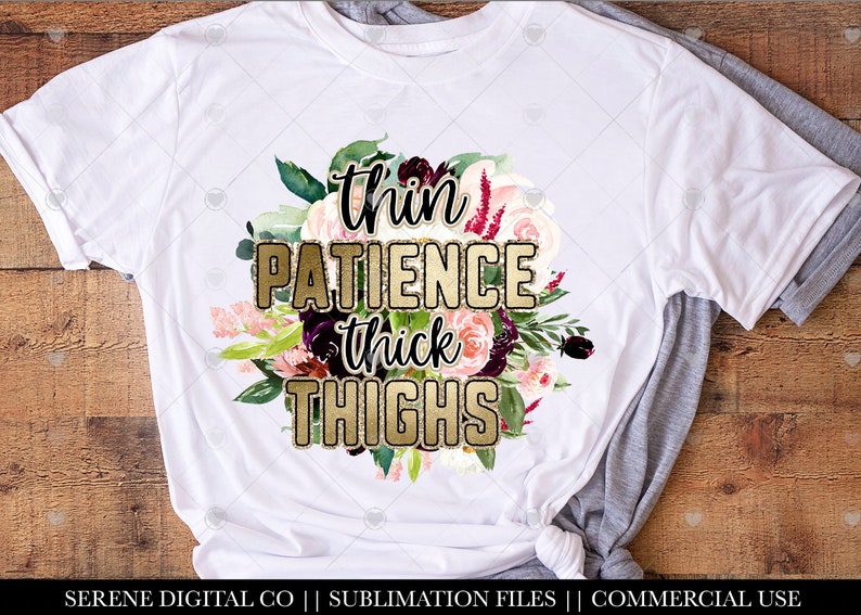 May include: White t-shirt with a floral design and gold glitter text that reads "thin patience thick thighs".