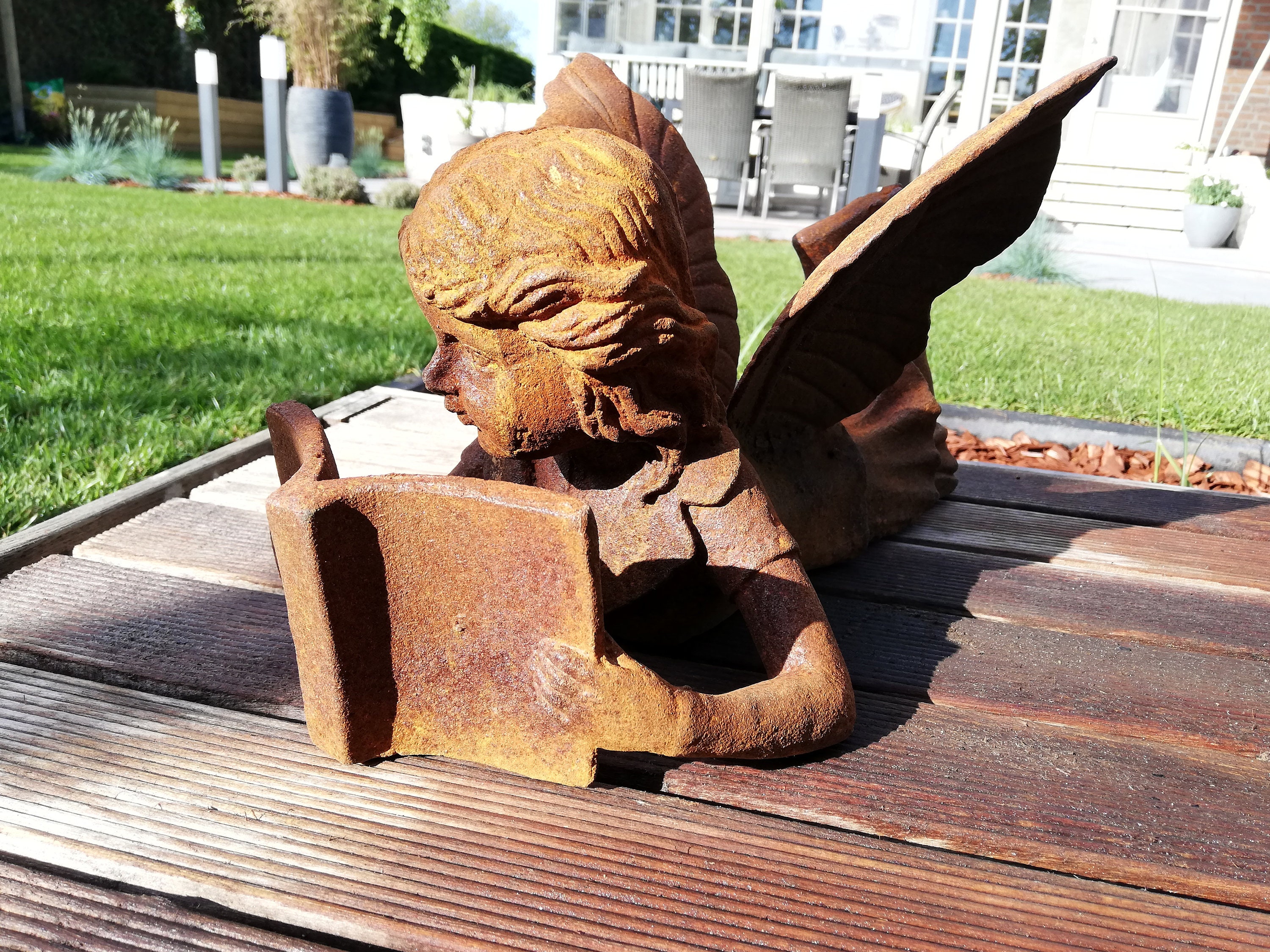 Antique looking garden sculpture of a fairy reading a book