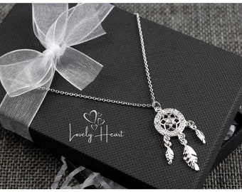 May include: Silver dreamcatcher necklace with a crystal design and feathers hanging from the bottom. The necklace is in a black gift box with a white ribbon.