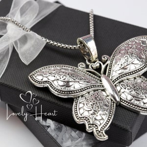 May include: A silver butterfly pendant necklace with an intricate design. The necklace is in a black gift box with a white ribbon.