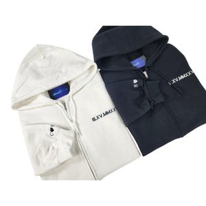 May include: Two zip-up hoodies, one white and one black, are shown. Both have a hood, a front zipper, and the Roman numeral "III.XV.MMXX" printed on the front. The white hoodie features a small heart and the letter "S" on the sleeve.