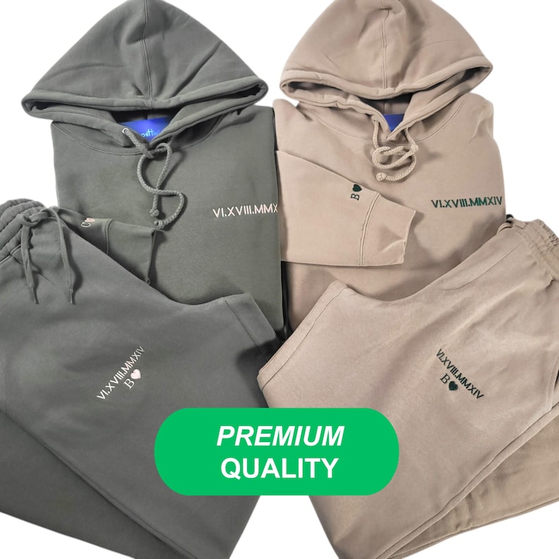 May include: Two matching sets of sweatpants and hoodies. One set is green and the other is beige. Both sets have the same Roman numeral text and a heart symbol on the front. The text reads "VI.XVII.VIII.MMXIV". The text is in green on the green set and in black on the beige set. The text is centered on the front of the hoodie and on the left leg of the sweatpants. The word "PREMIUM QUALITY" is written in white on a green rectangle.