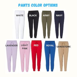 May include: Ten pairs of sweatpants in various colors, including white, black, army green, navy, lavender, light pink, red, royal blue, and sandstone. The sweatpants have a drawstring waistband and a relaxed fit.