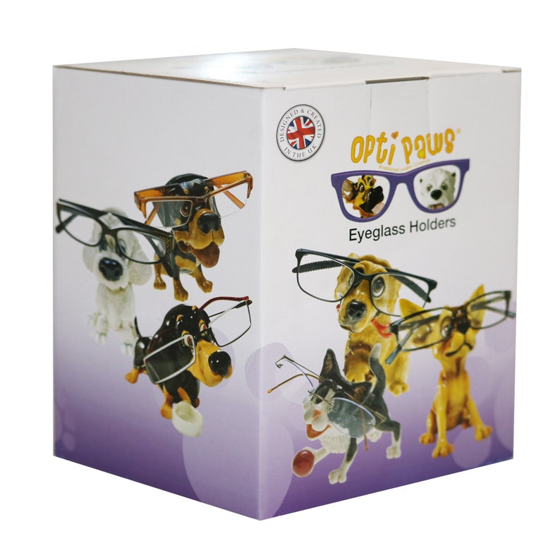 May include: A white box featuring eyeglass holders shaped like dogs wearing glasses. The box has the text "Opti Paws Eyeglass Holders" and a Union Jack logo. The eyeglass holders are various colors, including white, brown, and yellow.