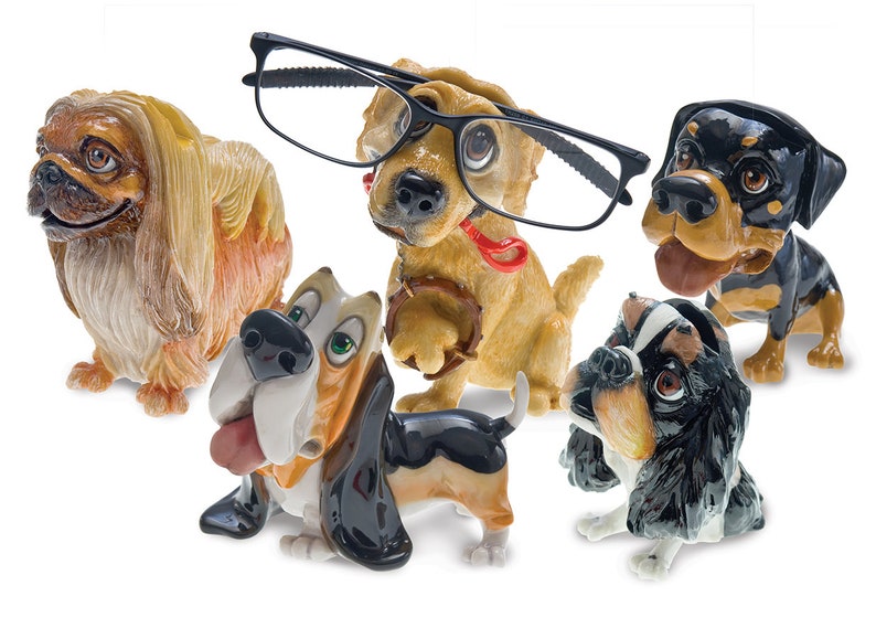 May include: A collection of ceramic dog figurines in various breeds, including a Pekingese, a Basset Hound, and a Rottweiler. One dog wears black-framed glasses. The figurines are painted with realistic details and vibrant colors.